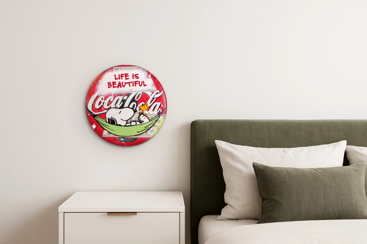 Rotes rundes Coca-Cola-Schild mit Snoopy und Woodstock in grüner Hängematte und dem Text „LIFE IS BEAUTIFUL“, als Kunstwerk an der Wand eines Schlafzimmers.