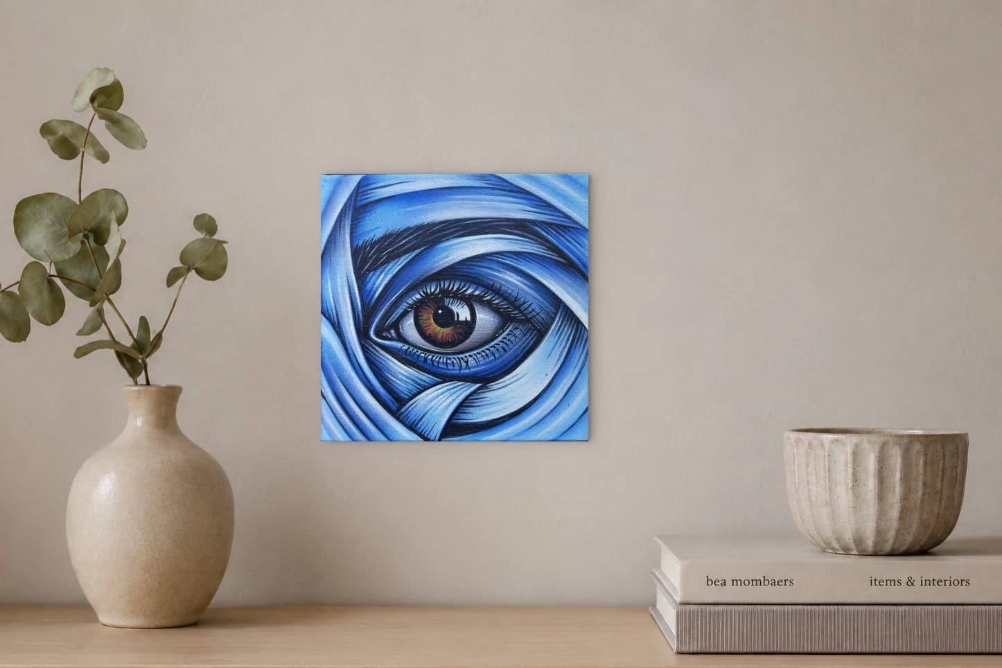 Nahaufnahme eines Auges mit brauner Iris und blauem Stoff, als Kunstwerk an der Wand eines hellen Raums.