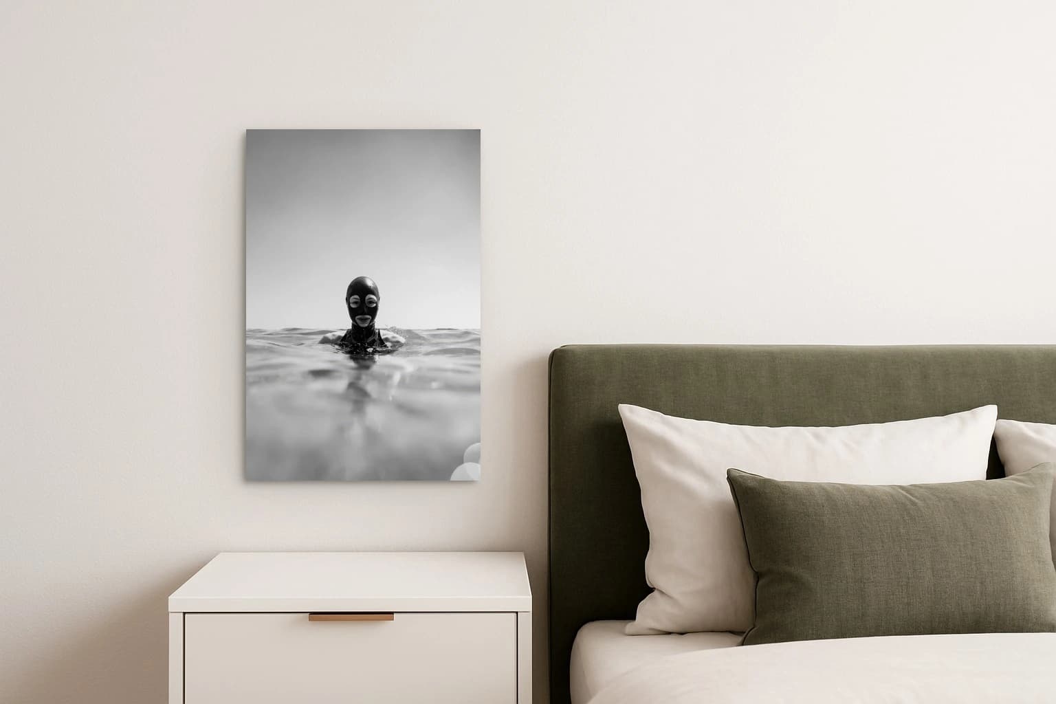 Eine Person in schwarzer Maske schwimmt frontal im Wasser vor hellem Hintergrund, als Kunstwerk an der Wand eines Schlafzimmers.
