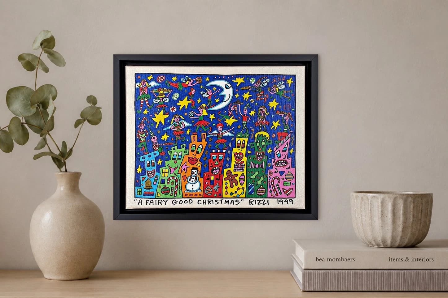Gerahmte bunte Weihnachtskunst mit Elfen, Sternen, Häusern und Schriftzug „A FAIRY GOOD CHRISTMAS“, als Kunstwerk an der Wand eines hellen Raums.