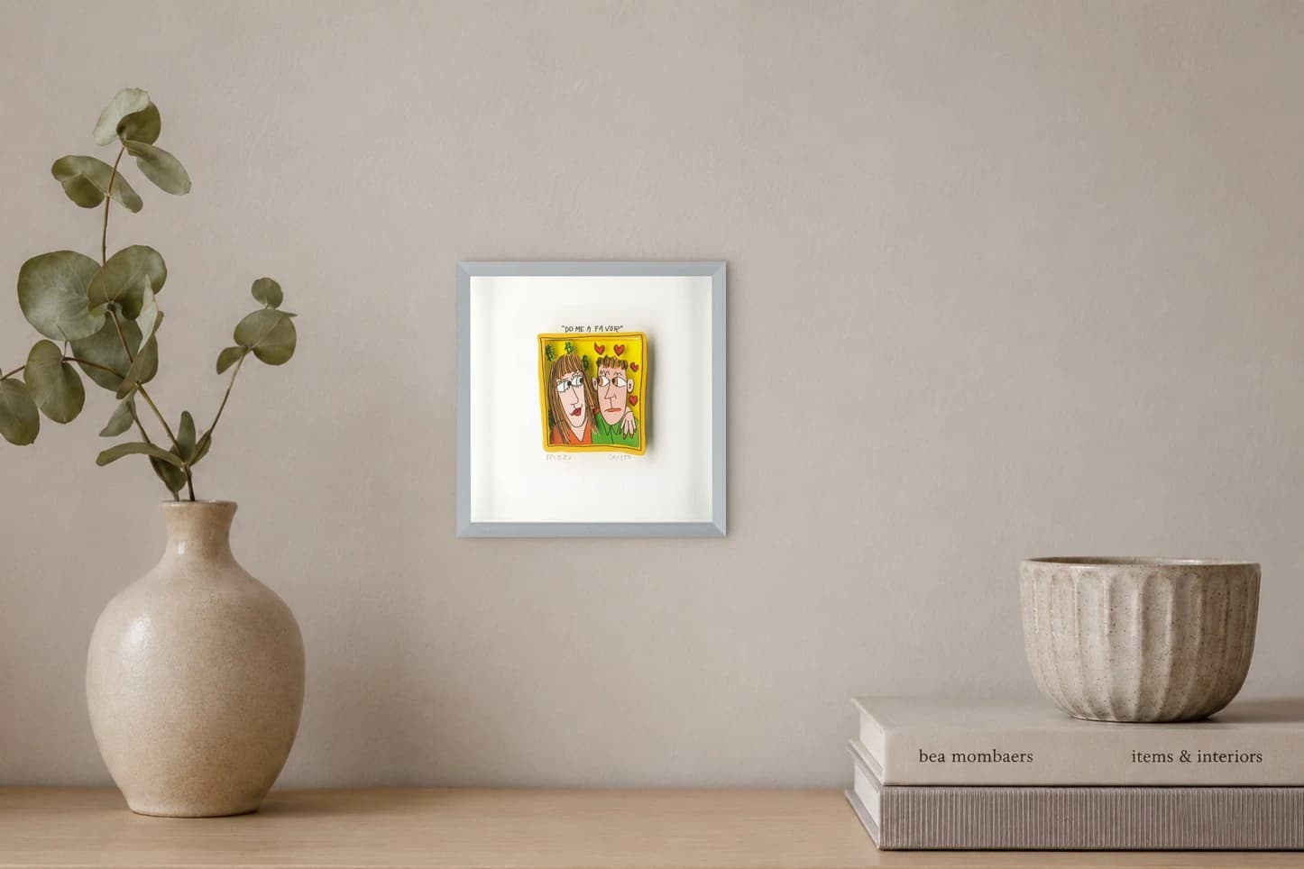 Gerahmtes Bild mit zwei Figuren, Herzen, Dollarzeichen und dem Text „DO ME A FAVOR“, als Kunstwerk an der Wand eines hellen Raums.