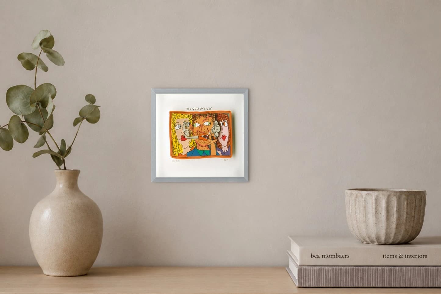 Gerahmte Zeichnung mit drei Gesichtern und dem Text „DO YOU MIND“, als Kunstwerk an der Wand eines hellen Raums.
