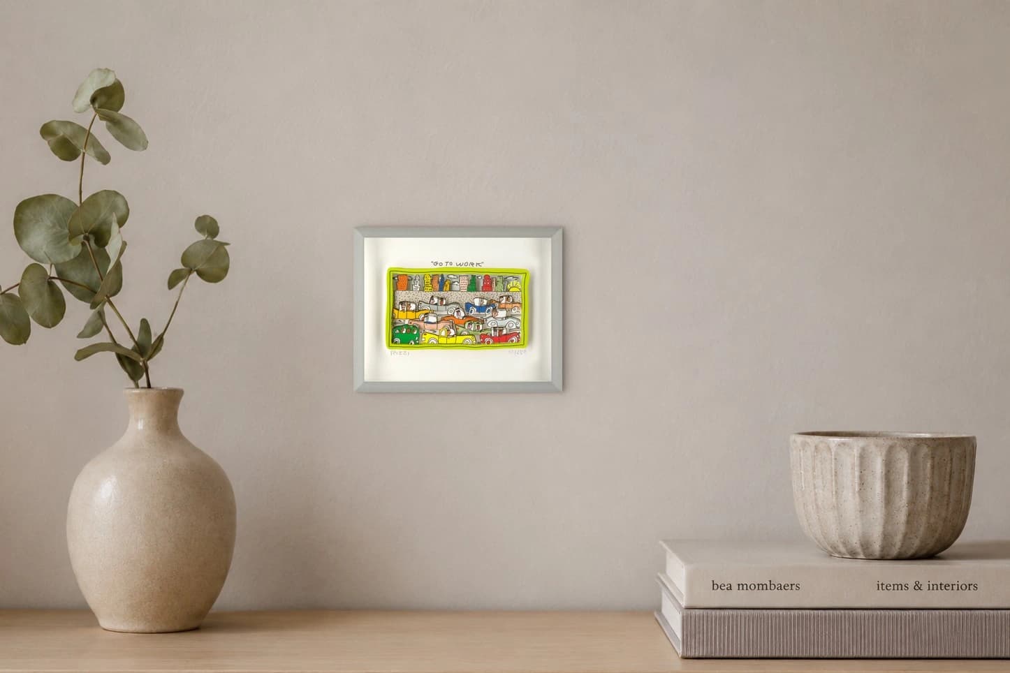 Gerahmtes Bild mit Stadt und vielen bunten Autos, darüber „GO TO WORK“ und Neonrand, als Kunstwerk an der Wand eines hellen Raums.