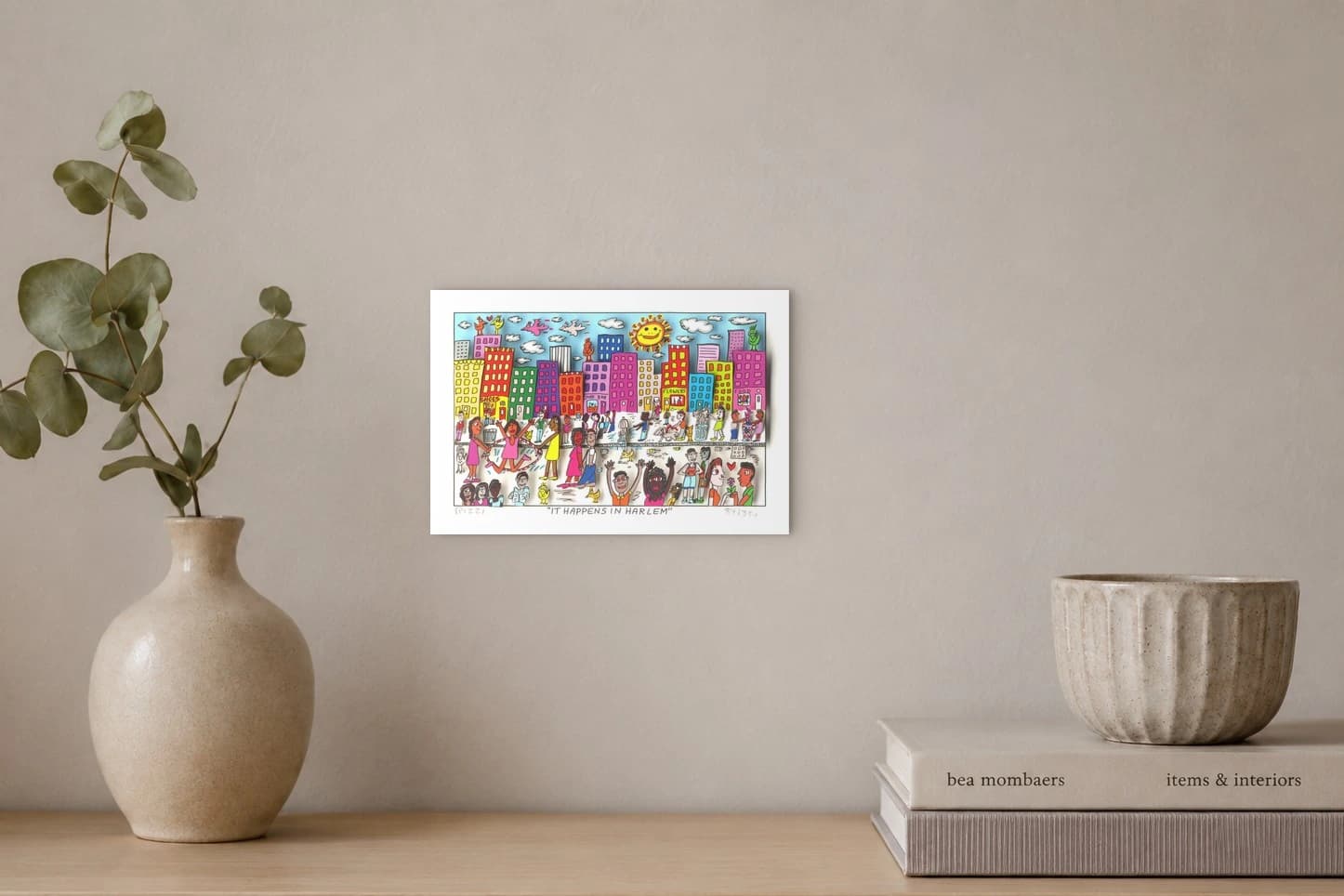 Bunte Straßenszene mit Menschen, Häusern, Sonne und Wolken sowie dem Schriftzug „IT HAPPENS IN HARLEM“, als Kunstwerk an der Wand eines hellen Raums.
