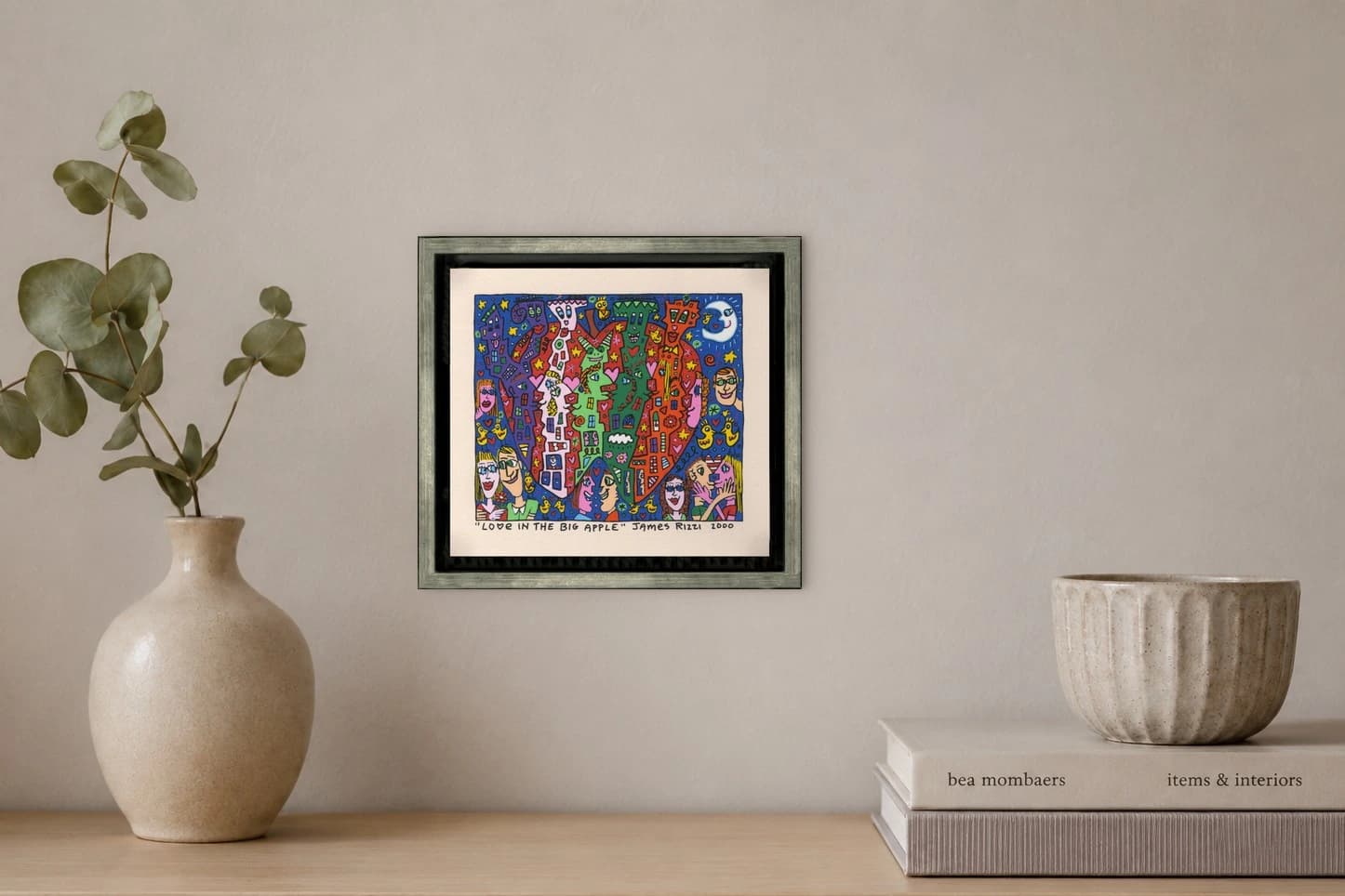 Gerahmtes Bild mit buntem Figurenmuster, Herzen, Sternen und Mond auf blauem Grund, als Kunstwerk an der Wand eines hellen Raums.