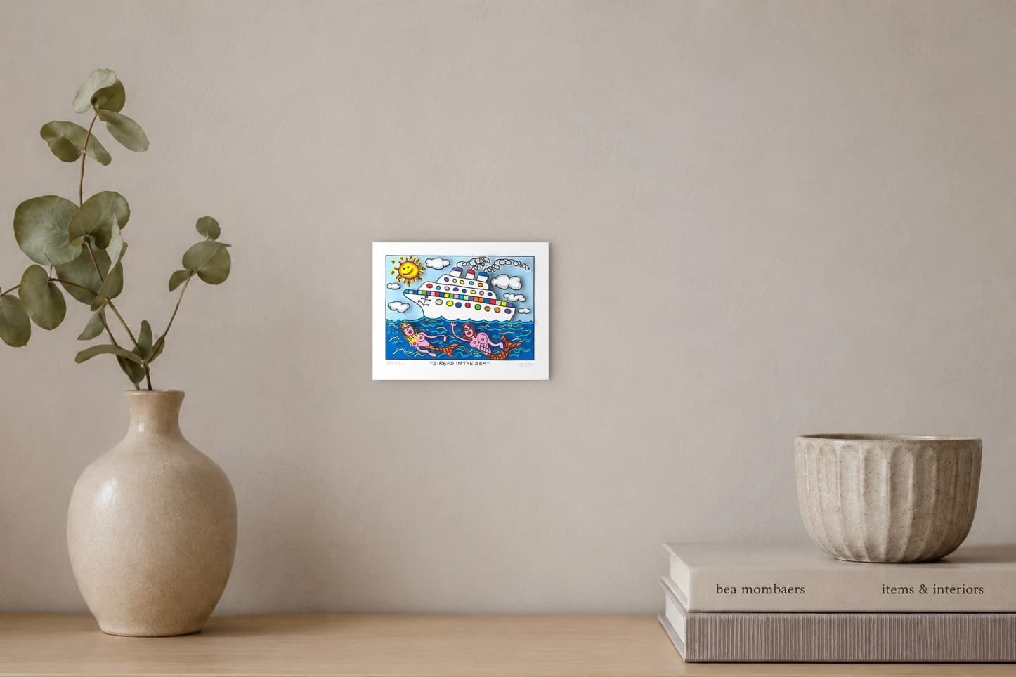 Weißes Kreuzfahrtschiff über zwei Meerjungfrauen im blauen Meer und Wolkenhimmel, als Kunstwerk an der Wand eines hellen Raums.