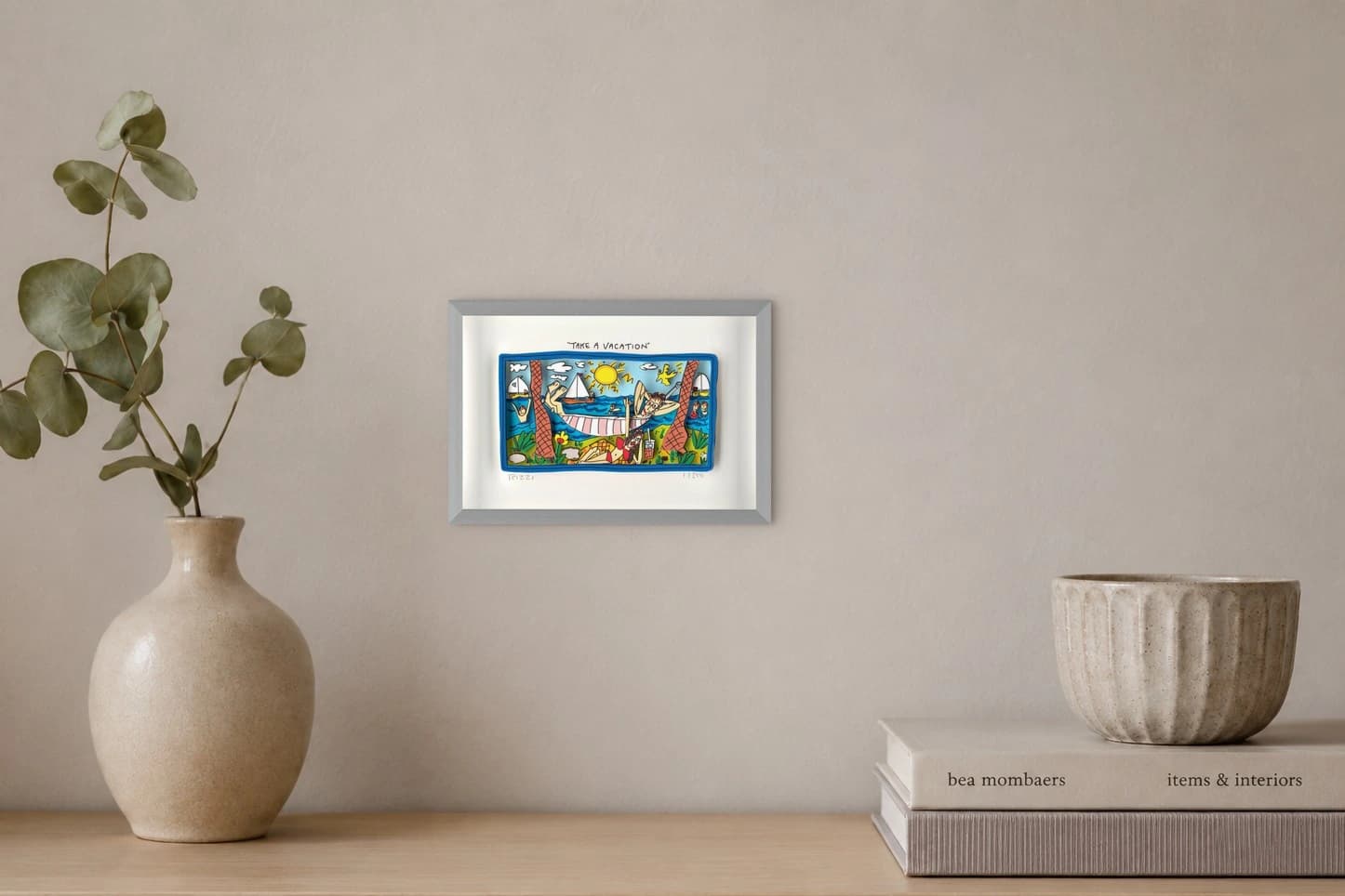 Gerahmte Strandszene mit Sonnenbadenden, Segelbooten, Palmen und „TAKE A VACATION“, als Kunstwerk an der Wand eines hellen Raums.