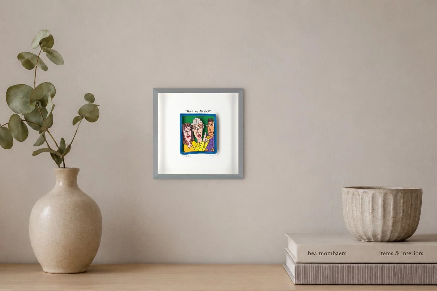 Gerahmtes Blatt mit drei gezeichneten Personen und dem Text „TAKE MY ADVICE“, als Kunstwerk an der Wand eines hellen Raums.