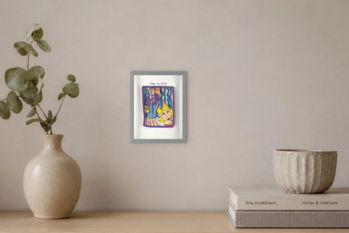 Gerahmte Zeichnung mit Mann, Frau und Text „TAKE MY WIFE“, als Kunstwerk an der Wand eines hellen Raums.