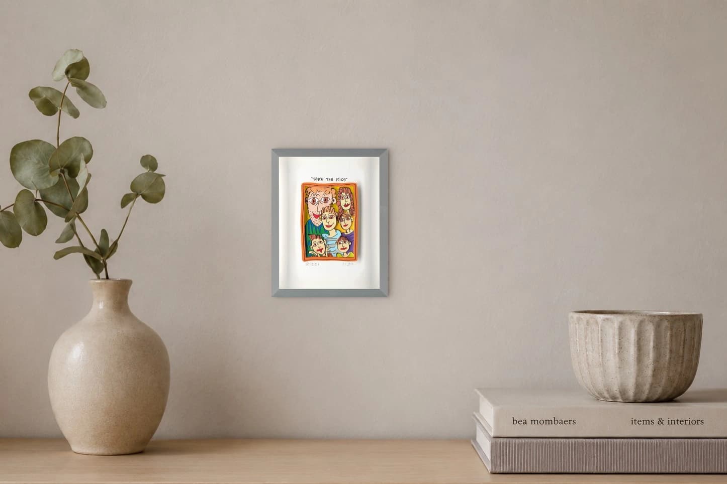 Gerahmtes Blatt mit „TAKE THE KIDS“ und buntem Familienbild im orangefarbenen Rahmen, als Kunstwerk an der Wand eines hellen Raums.