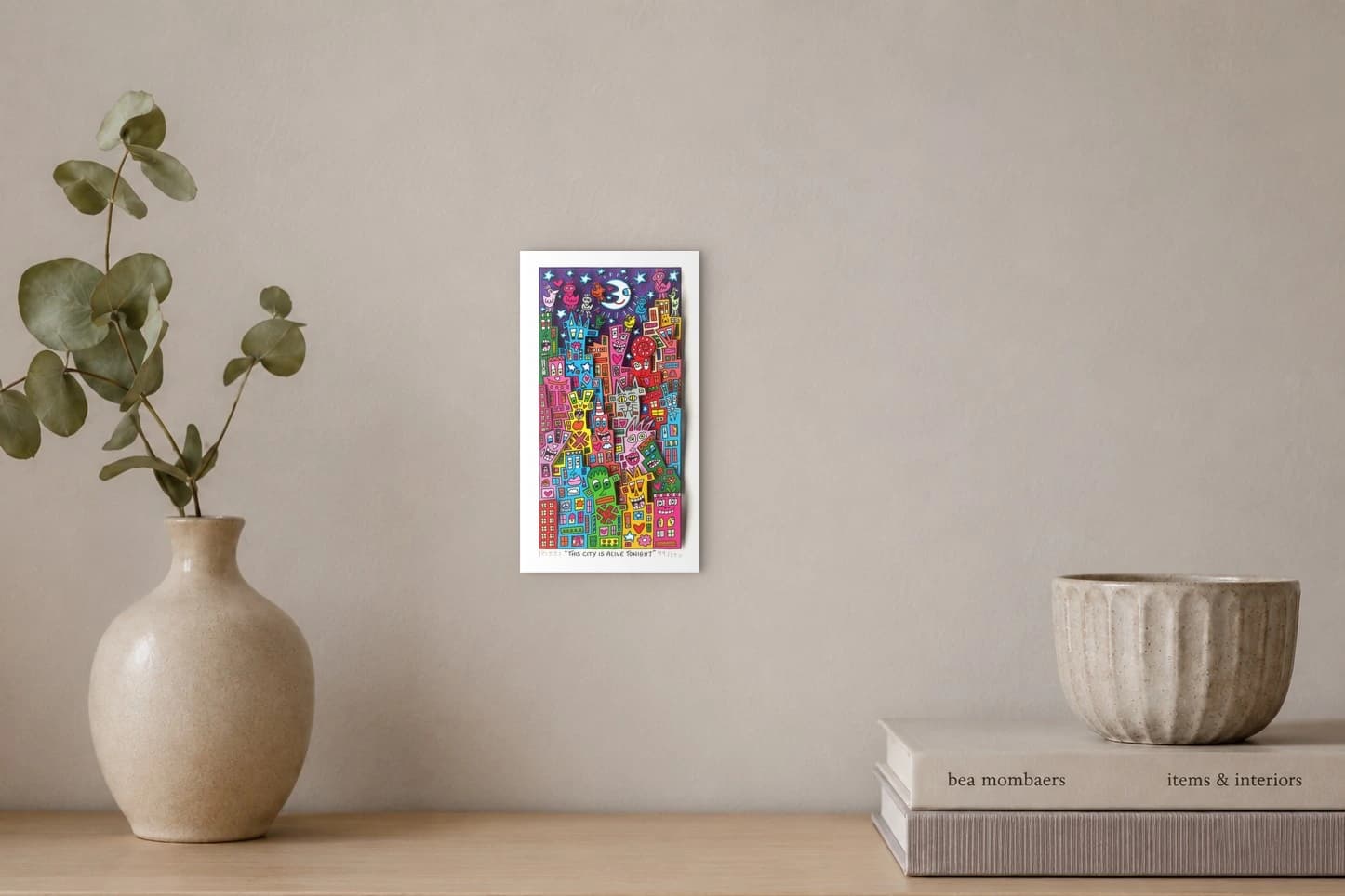 Bunte Häuser mit Gesichtern und Vögeln unter Mond und Sternen vor violettem Himmel, als Kunstwerk an der Wand eines hellen Raums.