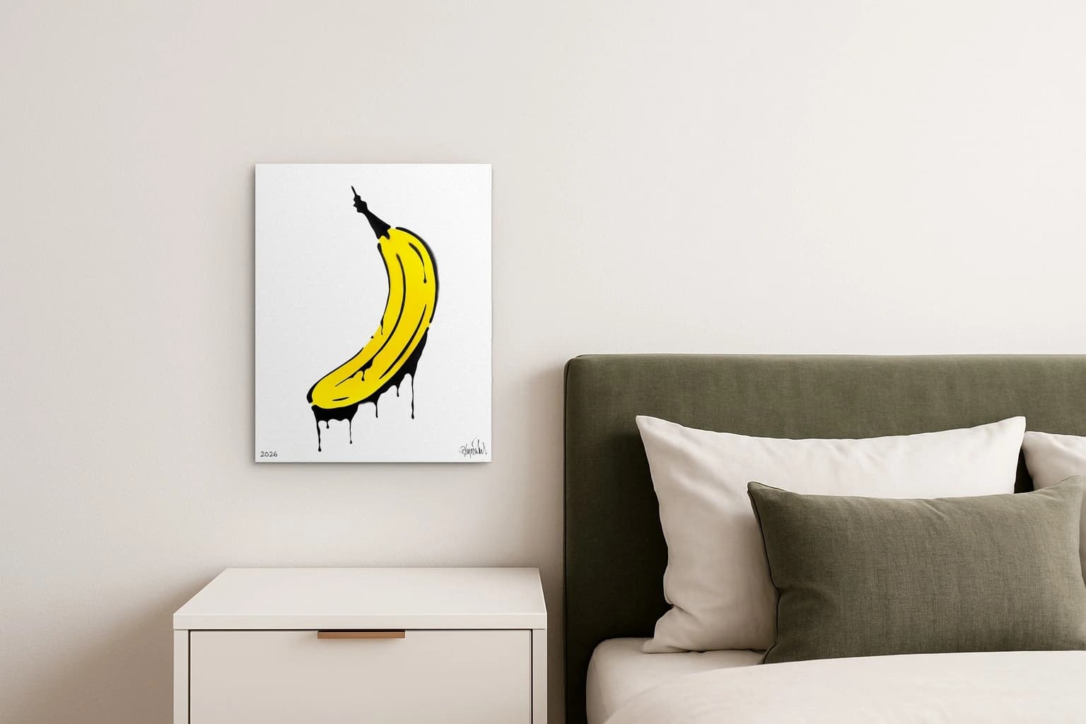 Gelbe Banane mit schwarzer Kontur und schwarzen Tropfen auf weißem Hintergrund, unten links 2026, als Kunstwerk an der Wand eines hellen Schlafzimmers.
