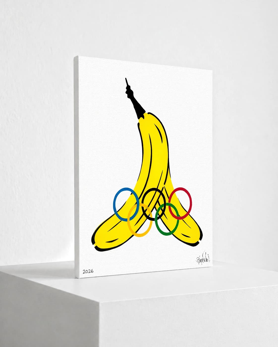 Gelbe Banane mit Olympischen Ringen auf weißem Hintergrund, unten links 2026 und unten rechts eine Signatur.