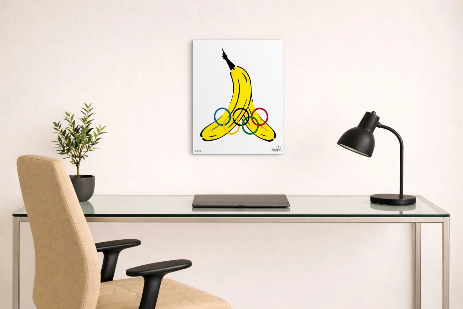 Gelbe Banane mit Olympischen Ringen, 2026 und Signatur auf Weiß, als Kunstwerk an der Wand eines Arbeitszimmers.