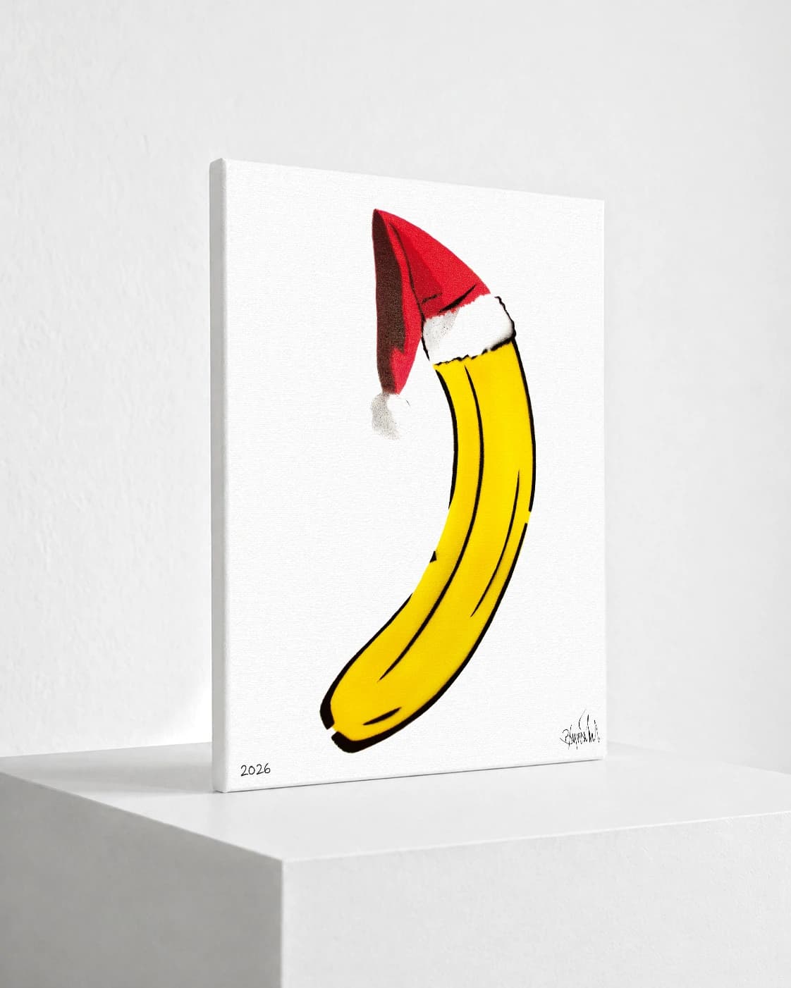 Gelbe Banane mit roter Weihnachtsmütze auf weißem Hintergrund, unten links 2026 und Signatur.