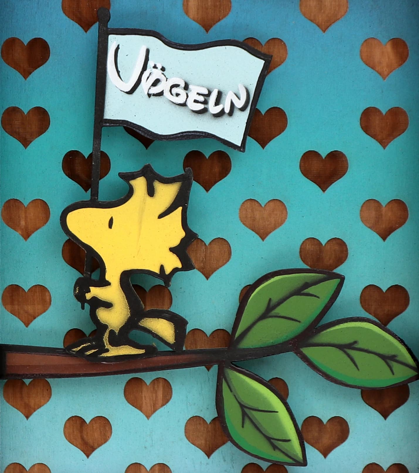 Woodstock auf einem Ast hält eine Flagge mit dem Wort „Vögeln“ vor blauem Herzmuster..