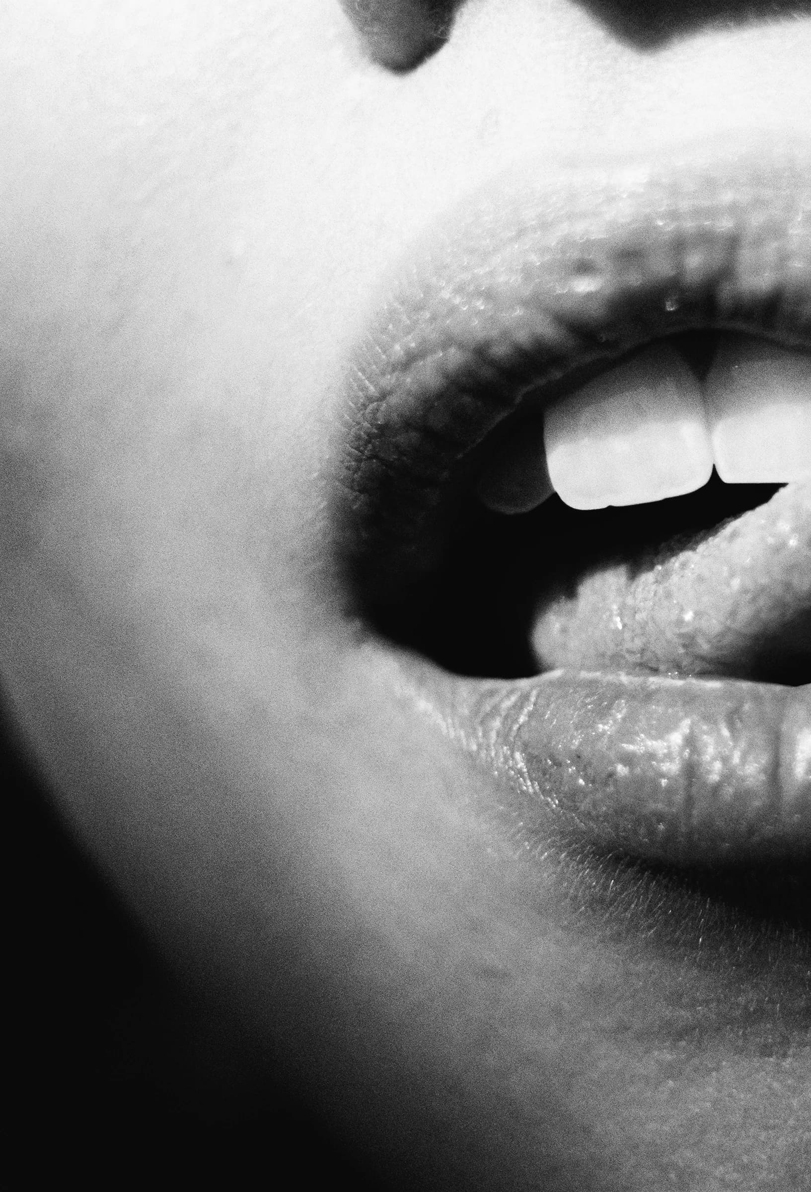Nahaufnahme eines geöffneten Mundes in Schwarzweiß mit Lippen und sichtbaren Zähnen.